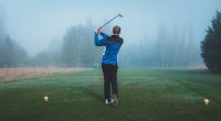 Golfer, der einen Trainingsanzug trägt, der an einem nebligen Tag Golf spielt, erhöht seine Chance, eine Golfverletzung zu bekommen