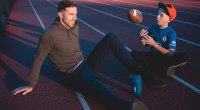 NFL-Quarterback für die Kansas City Chiefs sitzt auf dem Leichtathletikfeld, während sein Sohn einen Football hochwirft