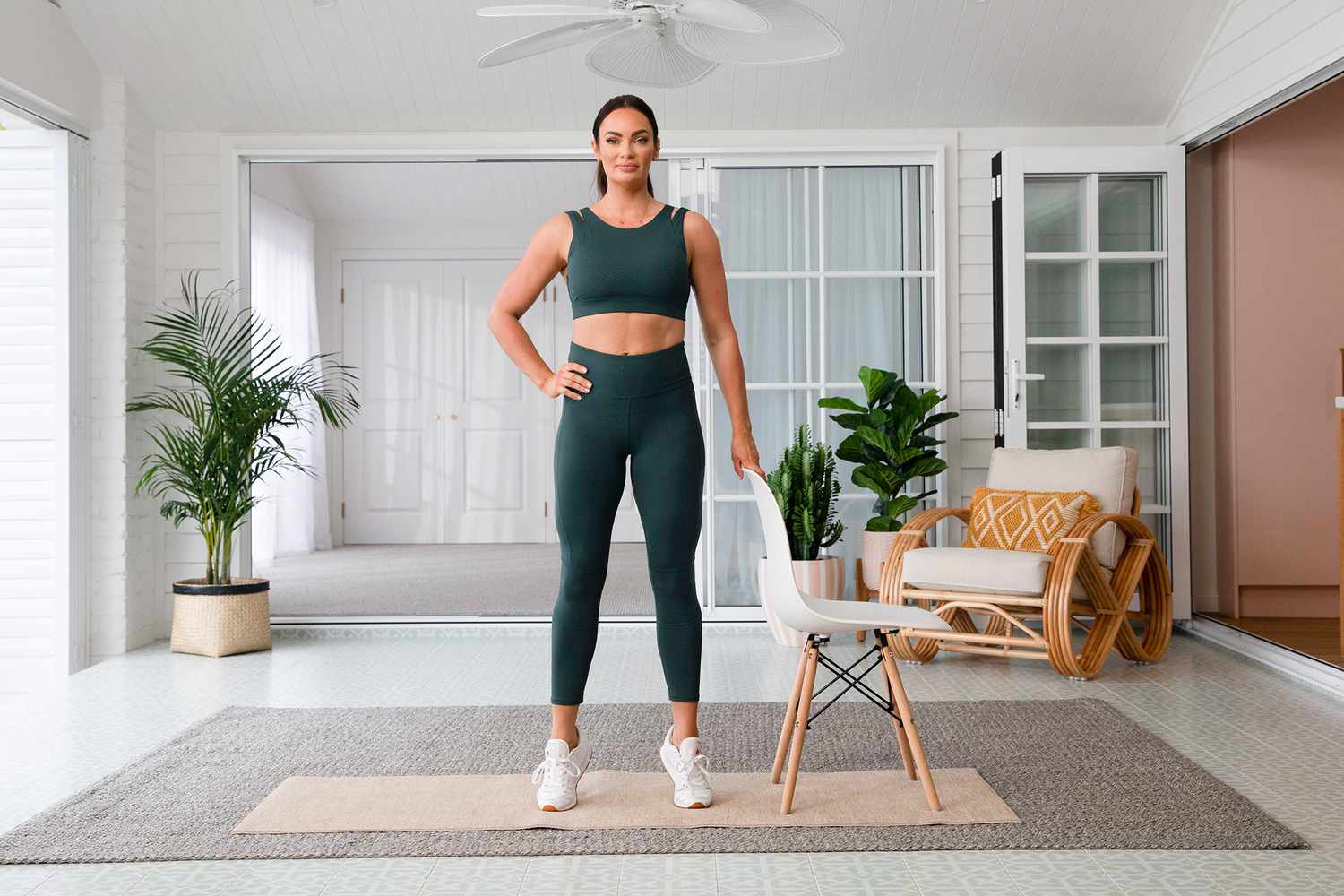 Frau im grünen Trainingsset, das neben dem weißen Stuhl Wadenheben macht